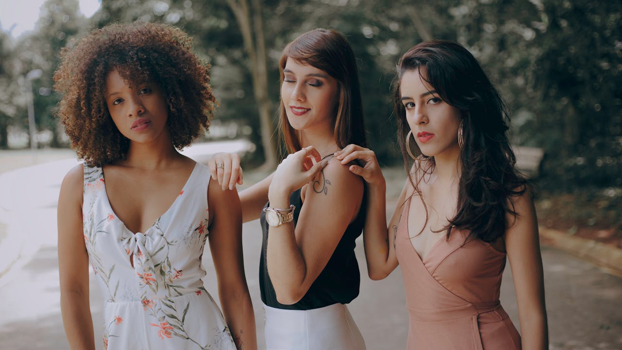 Three stylish women posing gracefully outdoors, showcasing summer fashion and elegant hairstyles.